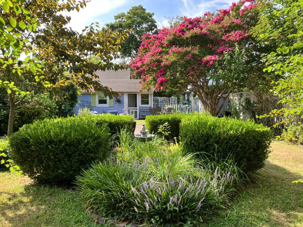 Cape may cottage surrounded by a lush summer garden