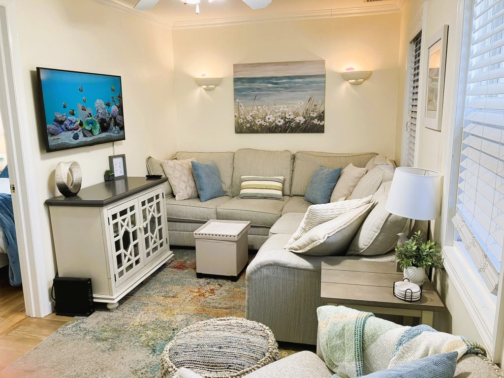 Living room with smart tv swivel chair ottoman and light beachy decor